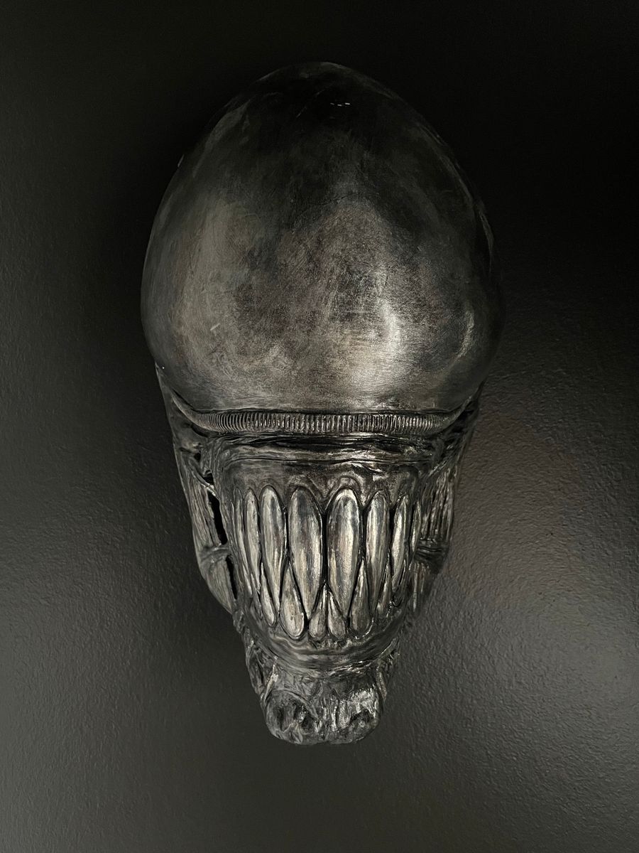 Crânio alienígena escuro e alongado, com fileira de dentes afiados